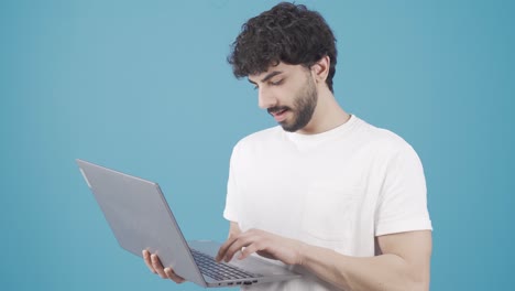 Young-man-standing-using-laptop-rejoicing,-looking-at-screen-and-smiling-at-victory.