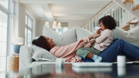 a mother and daughter laughing and playing on a couch together