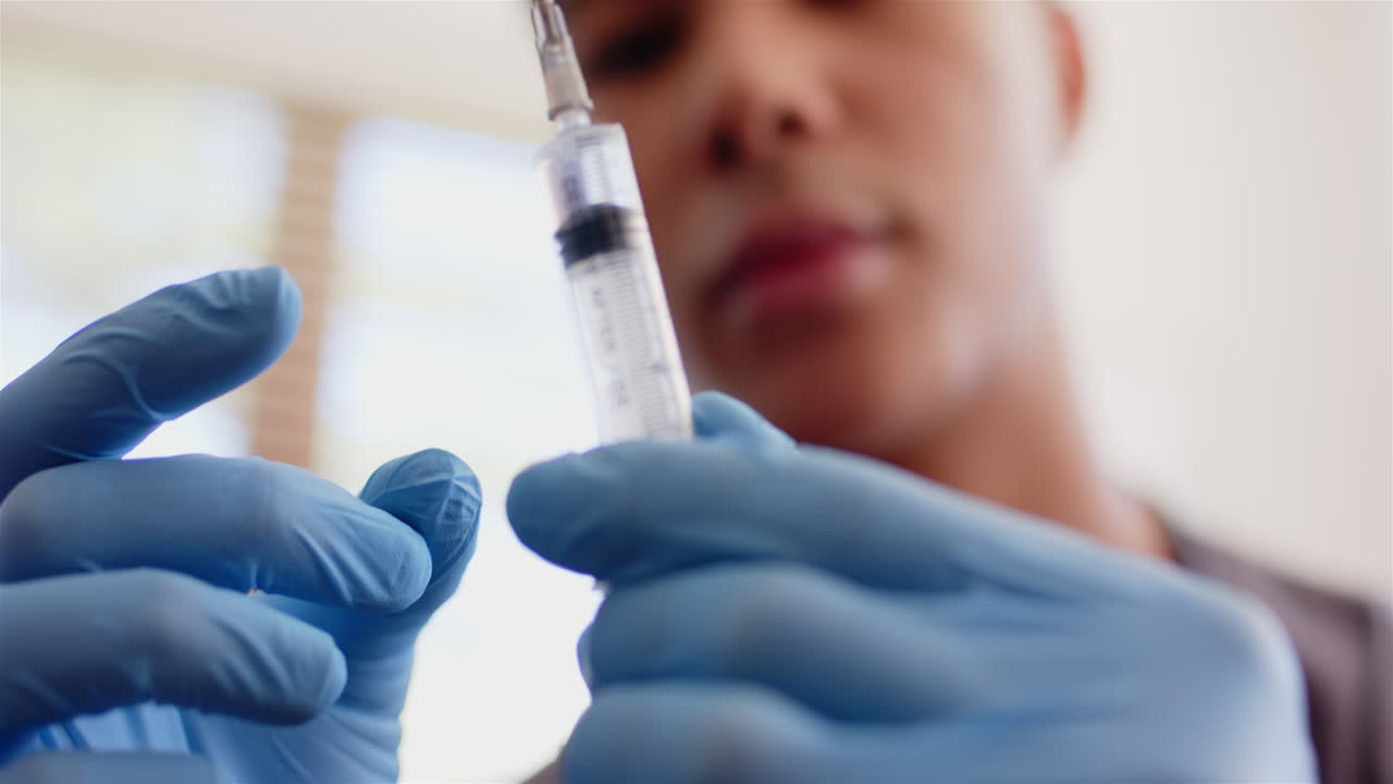 Preparing syringe for medical procedure, healthcare worker wearing gloves