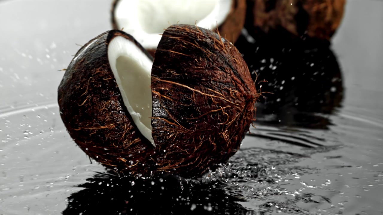 Noce di cocco fresca al rallentatore che cade e si spacca nell'acqua