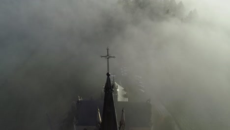 heavenly scene of neo-gothic church surrounded by eerie mist in poland, aerial