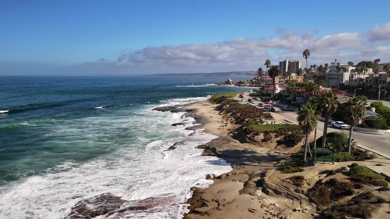 A smooth coastal flyover showing La Jolla’s sandy beach, clear waves, and bright California scenery