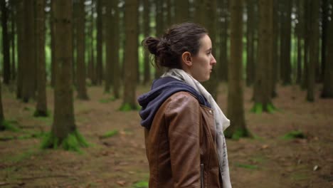 girl walking through a beautiful forest with tall green pine trees, side shot