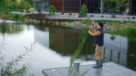 man fishing in a park by a modern building