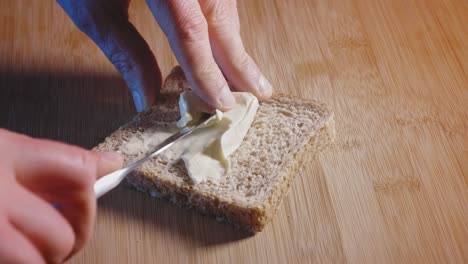 extendiendo el triángulo de queso en una rebanada de pan tostado integral con un cuchillo esparcidor