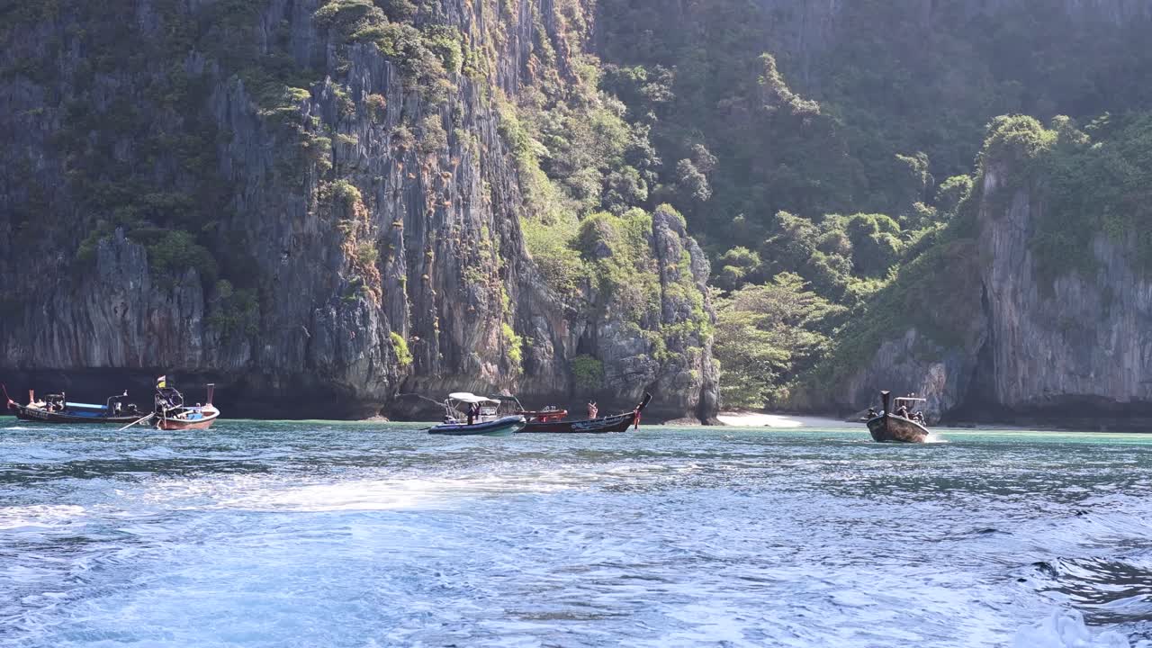barcos navegando cerca de una isla rocosa y exuberante