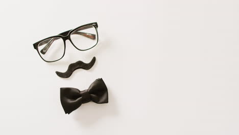 video de bigote falso negro, gafas y pajarita sobre fondo blanco con espacio para copiar