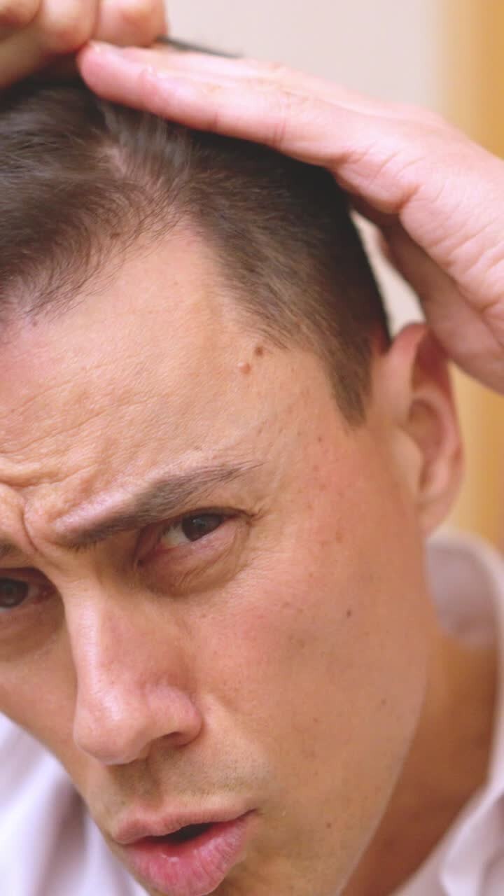 Handsome man combing hair and making funny faces