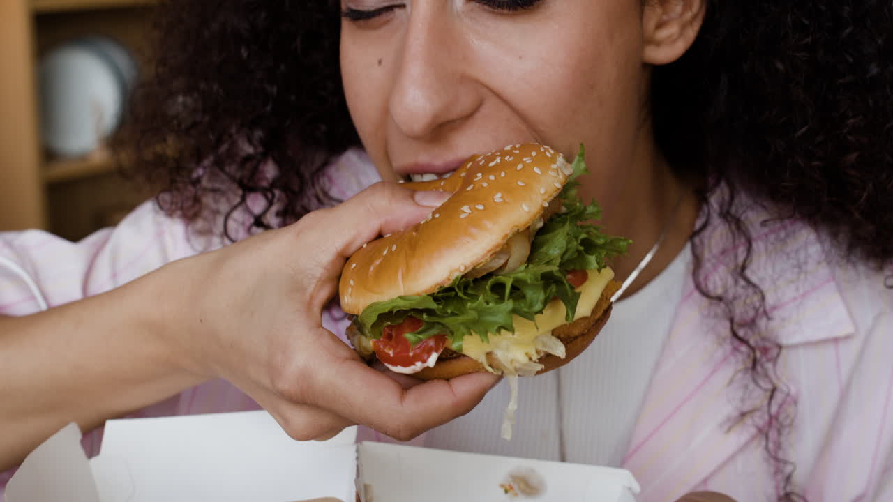 Close-up of a woman eating a messy burger