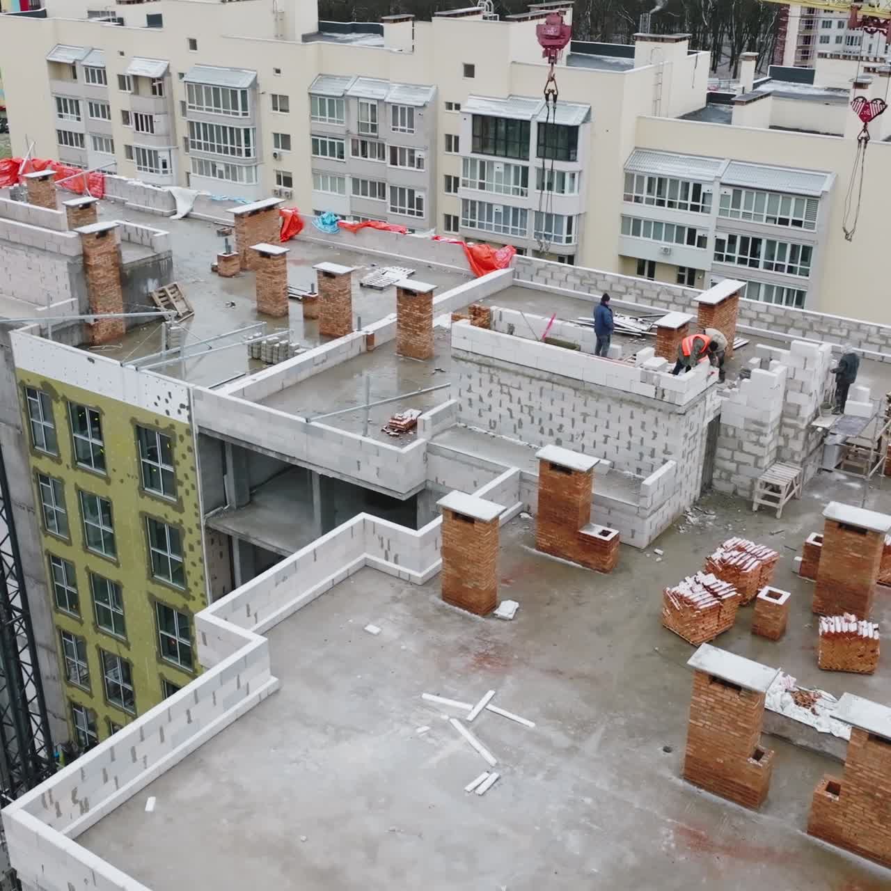 Building works on the roof of the apartment block. Building brigade working actively on top of the house. New construction in the residential area