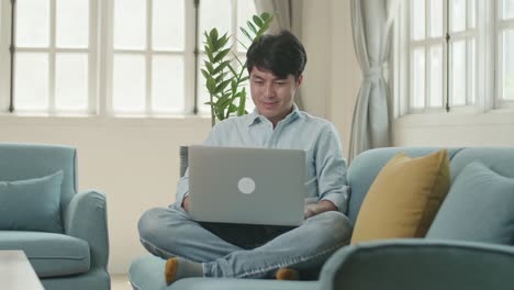 man sitting sofa and use laptop computer in home living room, video in 4k