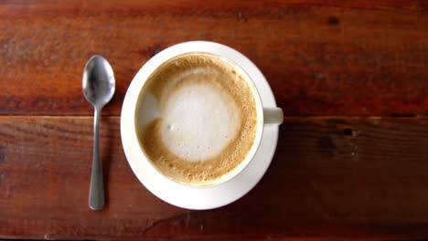 cup of coffee with saucer and spoon on table