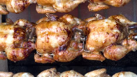 golden chickens roasting on a rotisserie grill