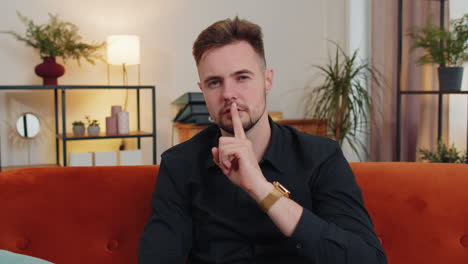 el joven presiona el dedo a los labios hace silencio signo de silencio no dice chismes secreto, tranquilo en casa