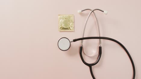 Video-Der-Nahaufnahme-Eines-Stethoskops-Mit-Kondom-Auf-Rosa-Hintergrund