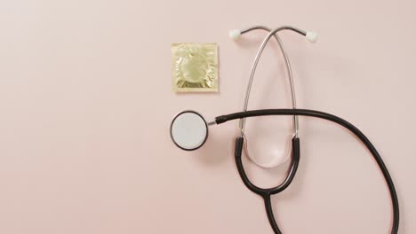 video of close up of stethoscope with condom on pink background