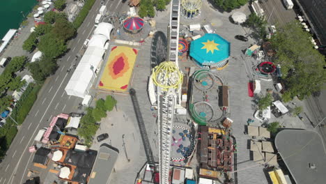 Close-aerial-drone-shot-descending-while-orbiting-around-amusement-park-free-fall-tower-in-Zürich,-Switzerland-during-Zürichfest