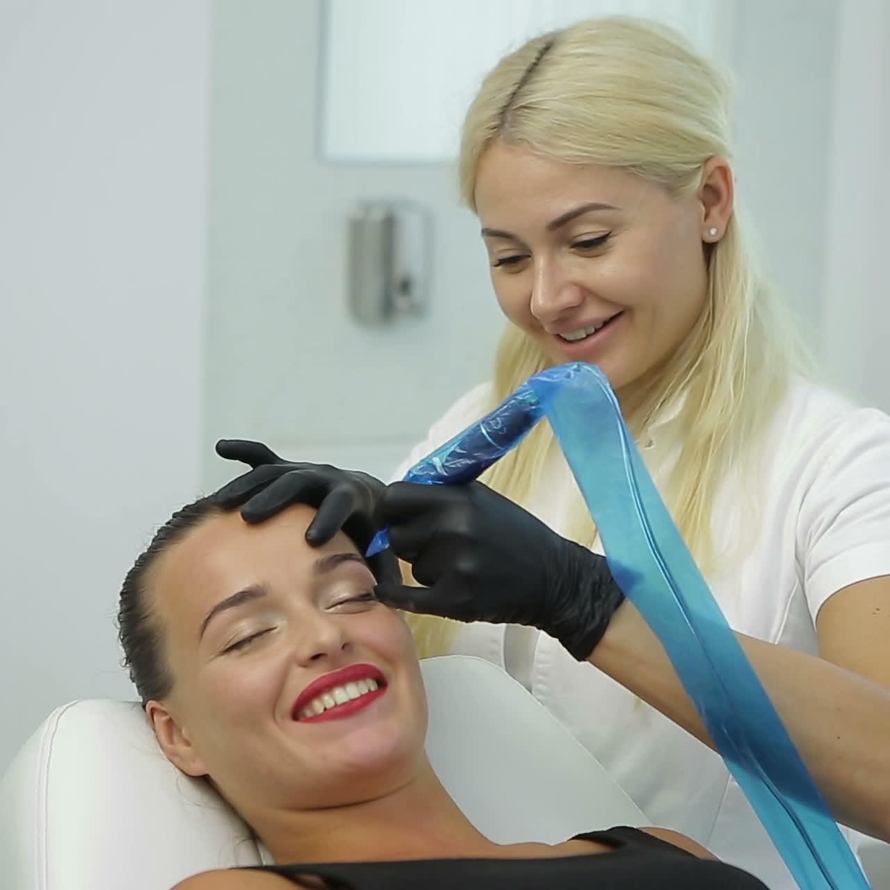 Cosmetologo che applica trucco permanente sul tatuaggio sopracciglia sopracciglia
