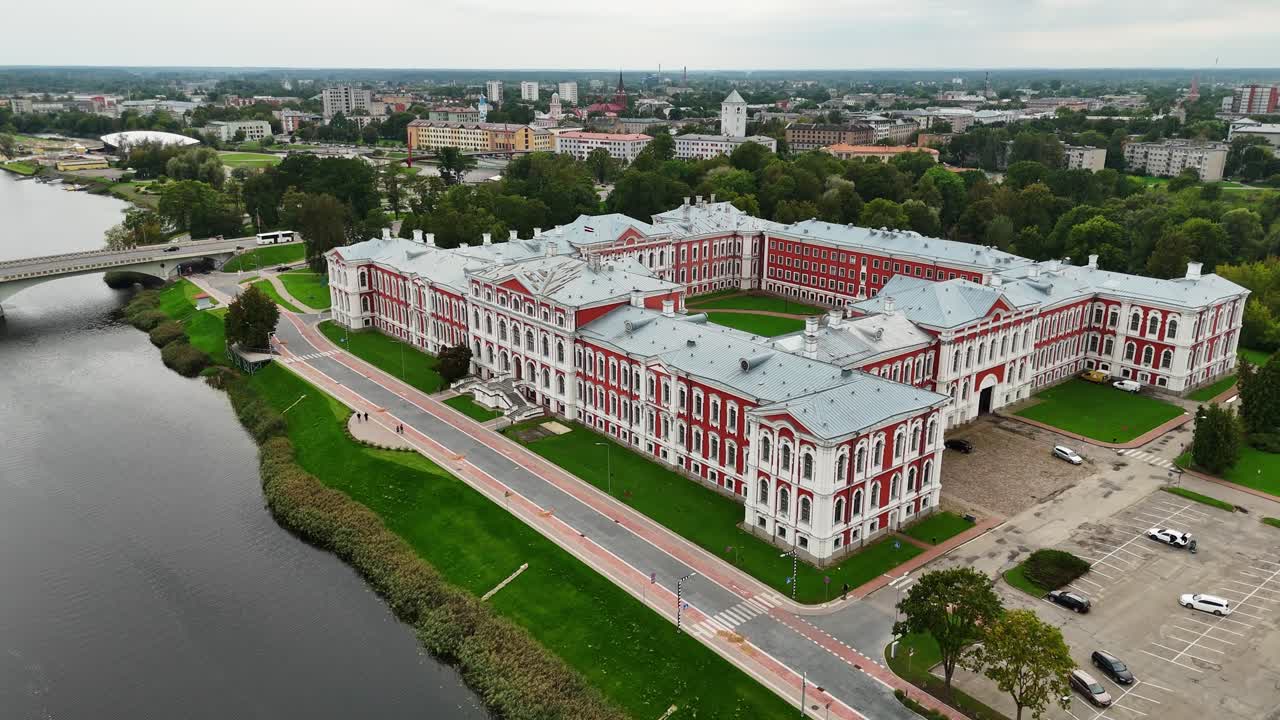 A drone pulls out from Jelgava Palace in Latvia, revealing its Baroque layout, central courtyard, and surrounding cityscape, highlighting architectural grandeur and urban layering