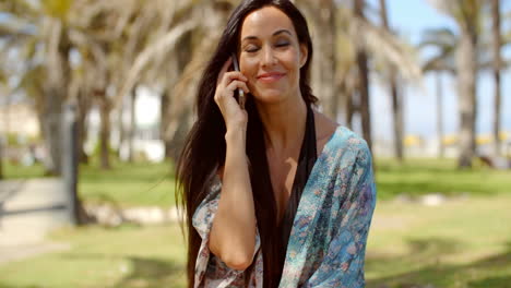 Happy-Lady-at-Grassy-Beach-Ground-Talking-on-Phone