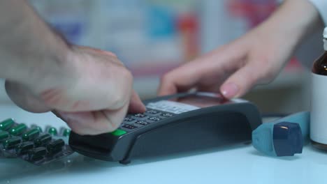 man buy medicament with card terminal at pharmacy. pos terminal at medical store