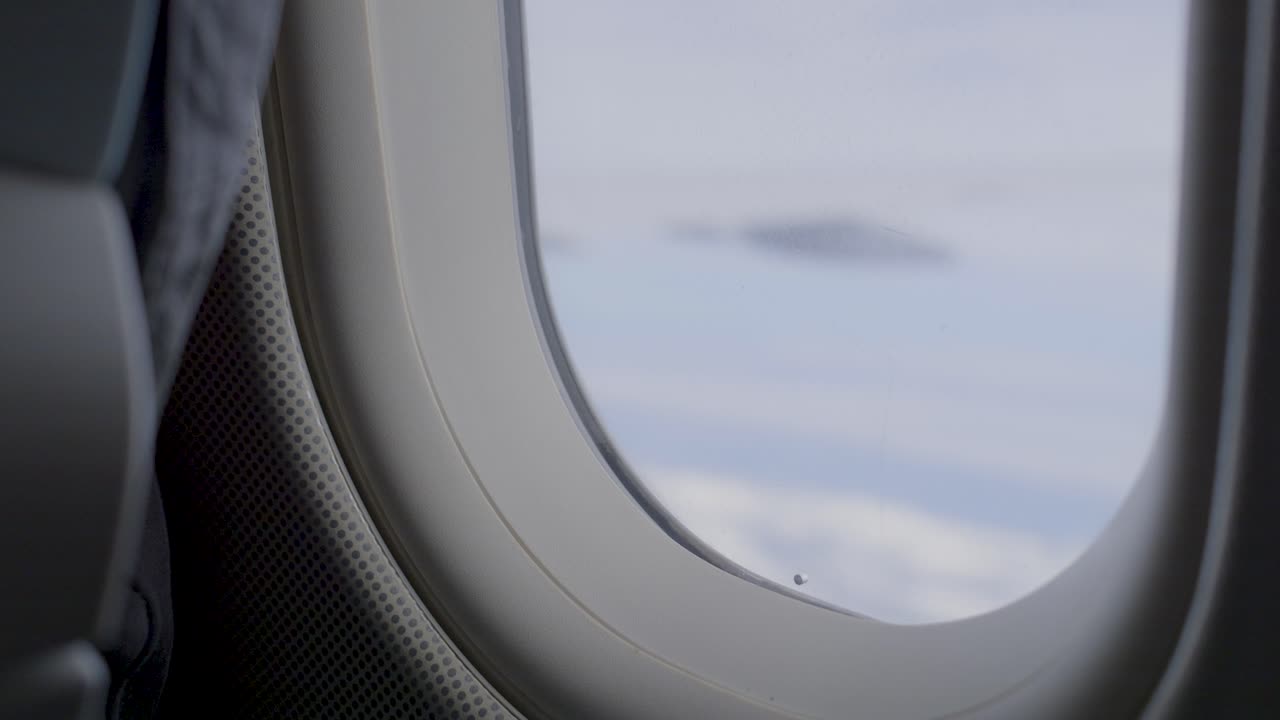 Looking out of an airplane window with a cloudy sky in the background