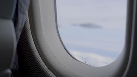 looking out of an airplane window with a cloudy sky in the background