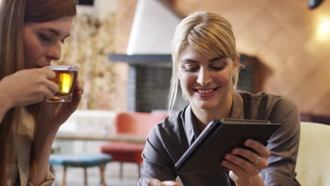 Mujeres-De-Negocios-Reunidas-En-Una-Cafetería-Usando-Una-Tableta-Digital