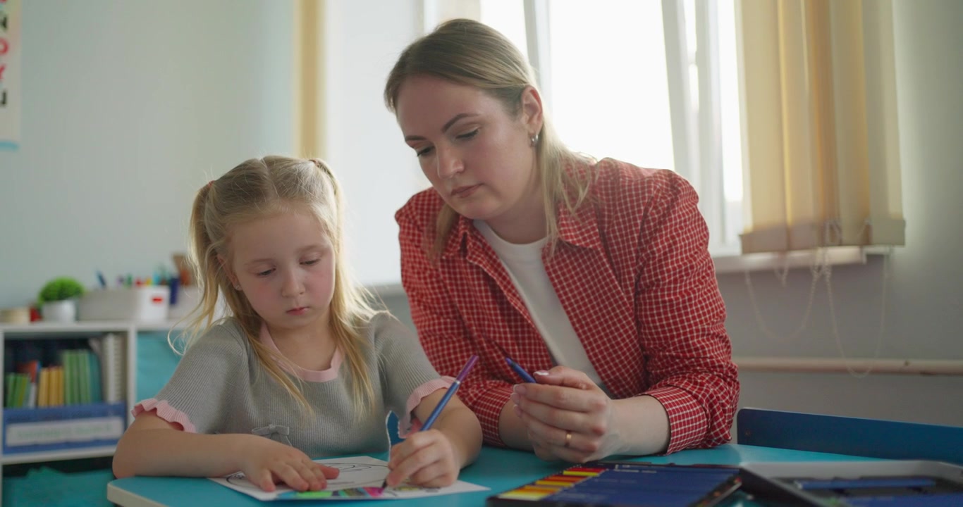 Insegnante che aiuta una bambina con un'attività di colorazione.