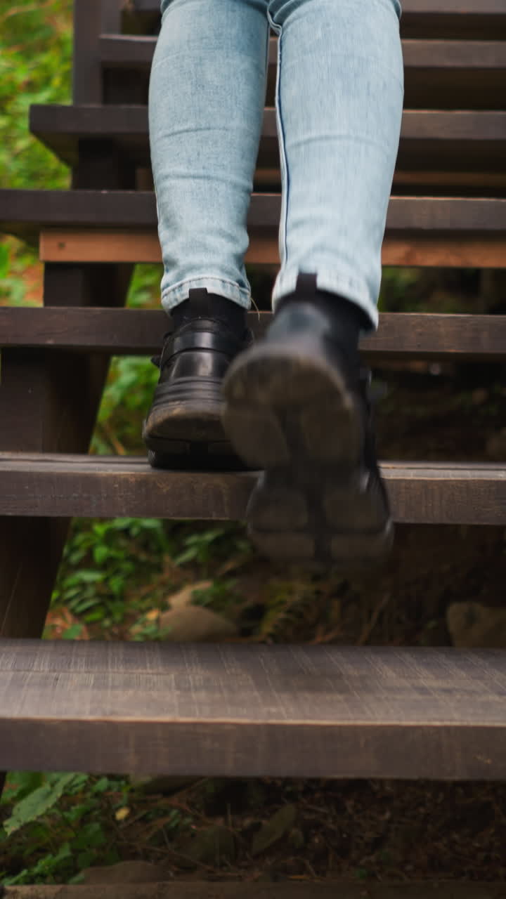 mujer en zapatillas de deporte pisando de escalera en escalera. joven llega a la cima de las escaleras en el camino a la casa de gampling. joven durante las vacaciones en el área del bosque