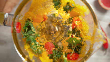 anti inflammatory vitamin smoothie with turmeric and fruit mixed in a glass blender, top view, inside of the device