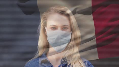 Animation-of-flag-of-france-waving-over-caucasian-woman-wearing-face-mask-in-city-street