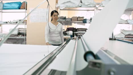 asian woman working with fabric cutter at textile factory