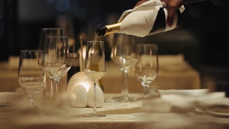 hand pouring expensive champagne into a champagne flute glass on the table - selective focus