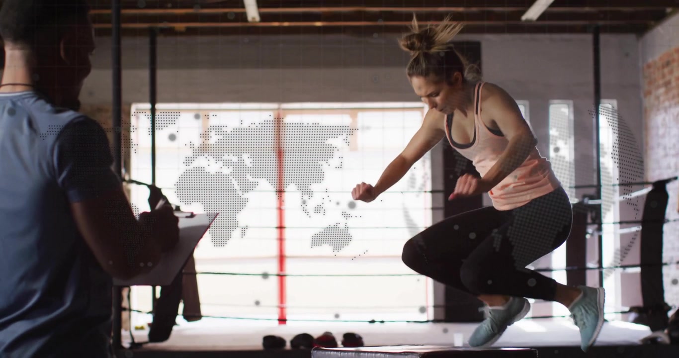 Female athlete wrapping hands, executing box jumps in boxing gym as trainer noting performance