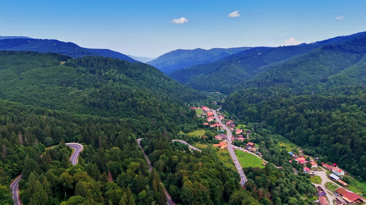 Village in lush mountains. A scenic view of a quaint village surrounded by dense forests and rolling hills, showcasing nature's beauty