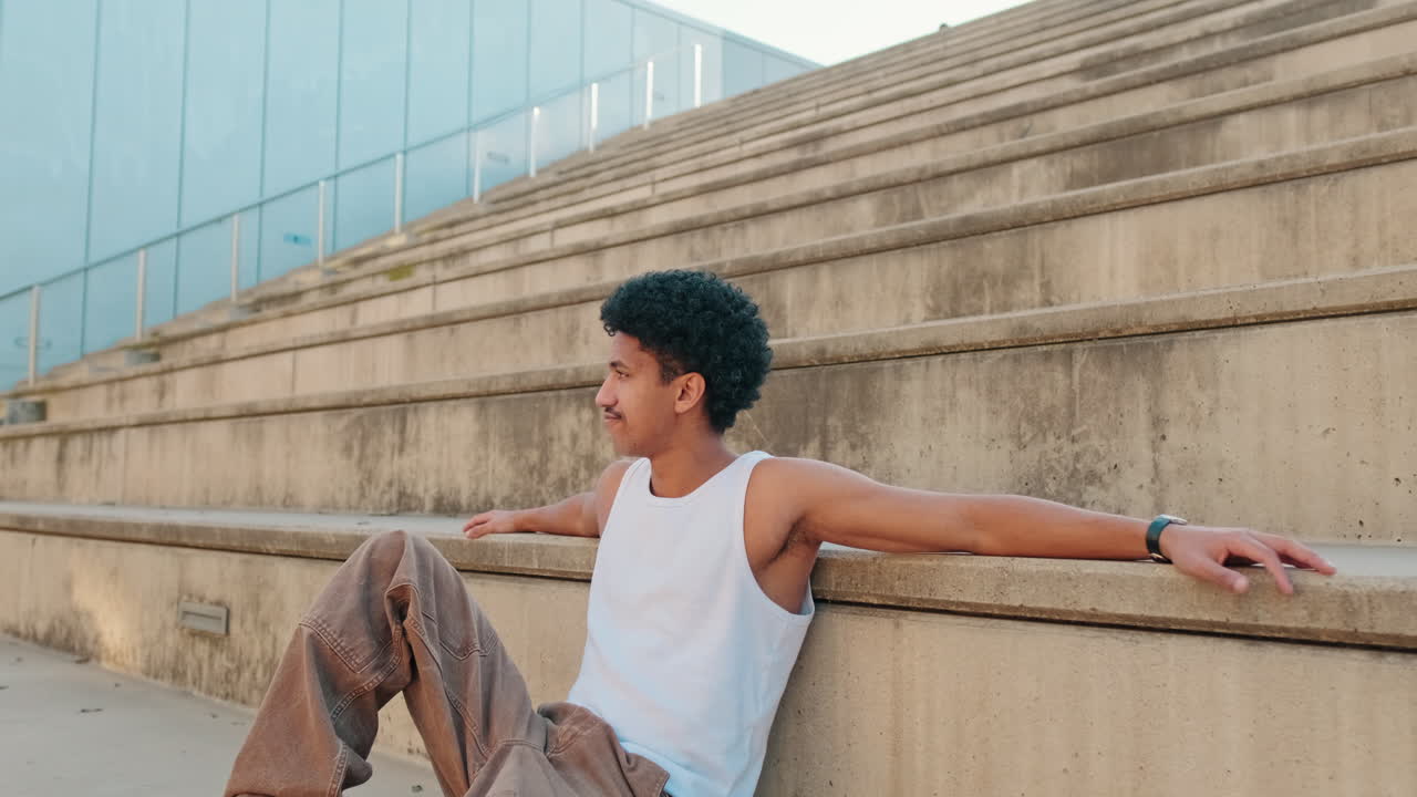 Young Man with Curly Hair Relaxing on Concrete Steps