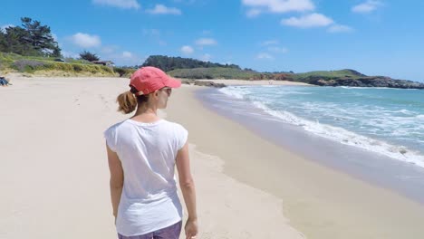 Young-woman-walking-on-a-beach-on-West-Coast,-USA