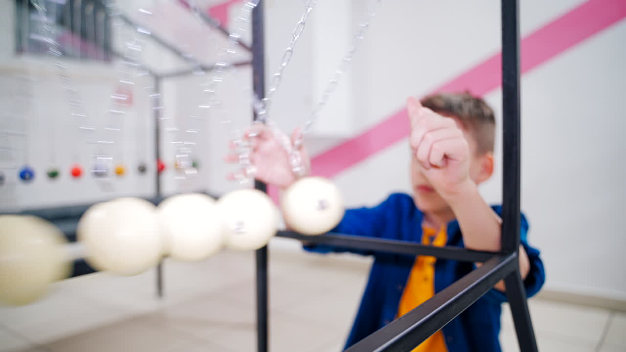 Boy makes an experiment with Newton's pendulum. The concept of physics. Museum of Science
