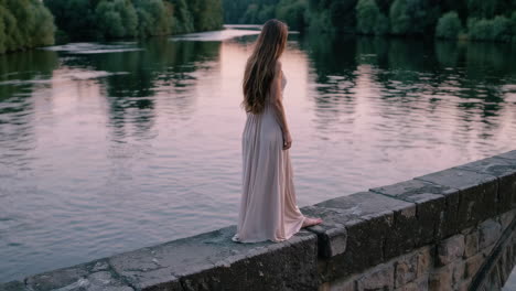 woman in a beige dress on a bridge at sunset