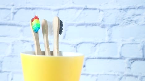 cepillos de dientes coloridos y de madera en una taza amarilla