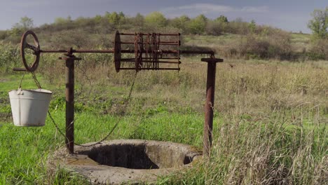 an old water well on rural homestead. an abandoned well in the middle of green grass and trees.