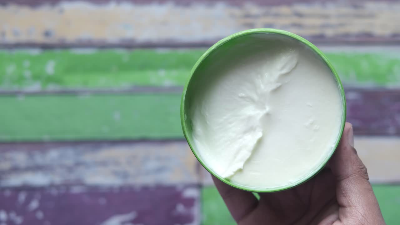 mano sosteniendo un recipiente de crema blanca