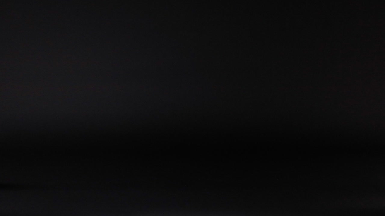 Tennis ball rolling across a dark surface