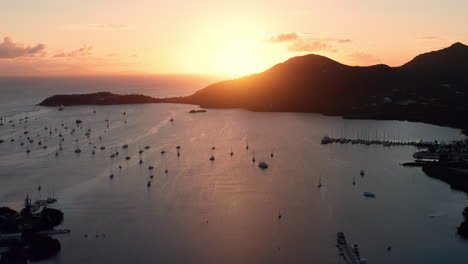 Toma-Aérea-De-La-Puesta-De-Sol-En-Puerto-Inglés-En-Antigua,-Caribe-Con-Vistas-De-Yates,-Veleros,-Puerto-Deportivo,-Bahía-Y-Acantilados