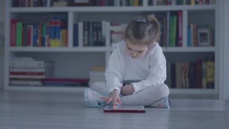 Interessiertes-Mädchen-Mit-Tablet-Auf-Dem-Boden