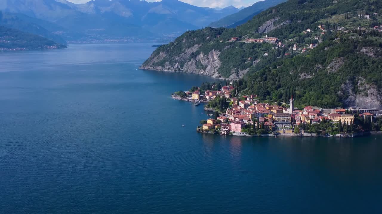video panorámico de drones en 4k de un pueblo a orillas del lago con los alpes en el fondo - lago como, italia