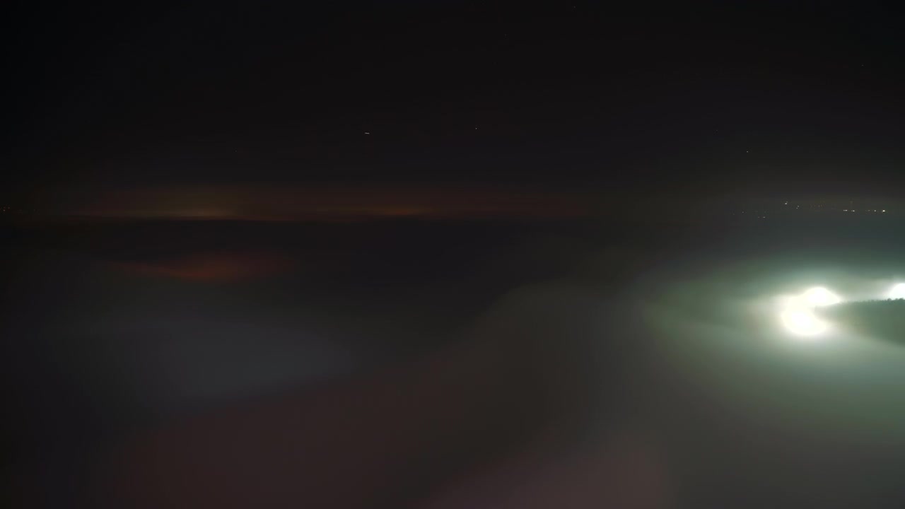 Timelapse de Nevoeiro Noturno Espalhando-se Sobre uma Paisagem Iluminada