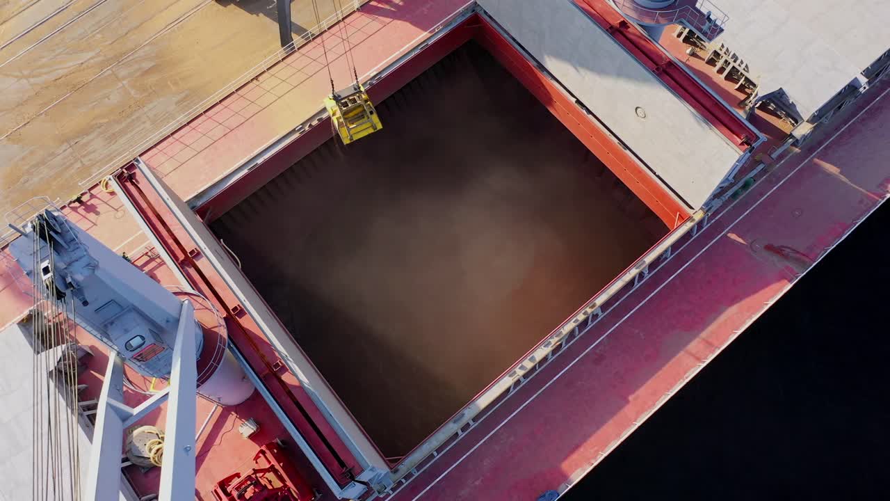 Cargo ship being loaded with grain by crane at sunny Baltic Sea port terminal