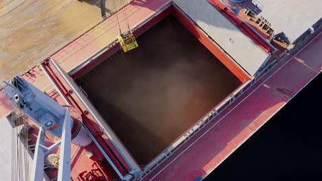 cargo ship being loaded with grain by crane at sunny baltic sea port terminal